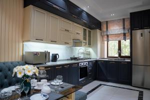 a kitchen with black cabinets and a table with flowers at Learmara Apartment #2 in Samarkand