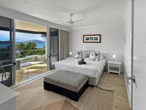 a white bedroom with a bed and a balcony at Beach Lodges in Hamilton Island +87 photos