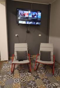 リマにあるCasa sabina hostelの壁にテレビが付いた部屋の椅子2脚