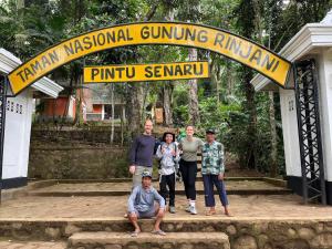 a group of people standing under a sign at a temple at Ila Homestay in Senaru