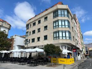 a building with tables and umbrellas in front of it at Apartamento Pedra Pateira in Ribeira