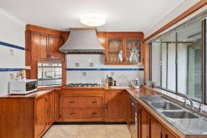 a kitchen with wooden cabinets and a sink at Hacienda Retreat- 27 guests in Capel Sound