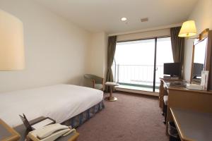 Shimonoseki Grand Hotel في شيمونوسيكي: غرفة فندقية بسرير ونافذة كبيرة