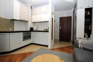 a kitchen with white cabinets and a living room at Apartment Classic Comfort in Elblag