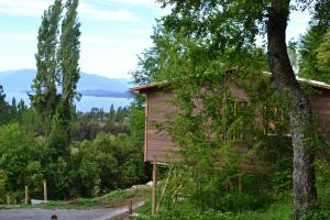 una cabaña de madera con un árbol al lado en Cabañas Mas Ke Miel, en Lago Ranco