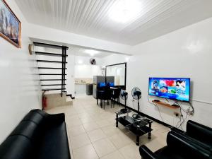 a living room with a black couch and a tv at Calapan Transient Maple L82 in Calapan