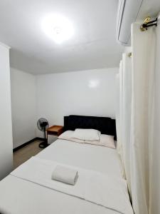 a white bed in a white room with a lamp at Calapan Transient Maple L82 in Calapan +28 photos