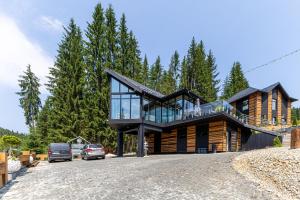 a house on a hill with cars parked in the driveway at Шишка in Bukovel