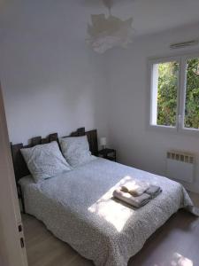 a bedroom with a bed with a blanket and a window at Maison 4 chambres in Eysines