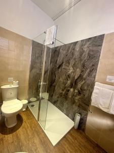 a bathroom with a toilet and a glass shower at The Tudor Hotel in Bridgwater