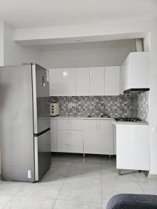 a kitchen with white cabinets and a refrigerator at Gonio Apartment Seaview in Kvariati +4 photos