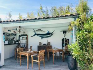 a patio with tables and chairs and a shark on the wall at Le Jardin des Portes in Les Portes