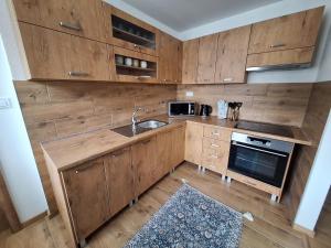 a kitchen with wooden cabinets and a sink at Farmársky apartmán Agrofarma Dianiška in Tisovec +6 photos