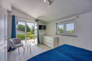 a bedroom with a bed and a chair and a window at Apartments Galeb in Poreč