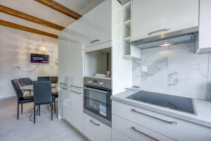 a kitchen with white cabinets and a table with chairs at Apartments Galeb in Poreč