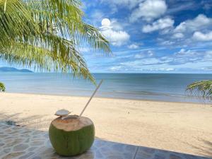 una noce di cocco seduta sulla spiaggia con una paglia di Sangjun On Beach Resort a Bang Saphan