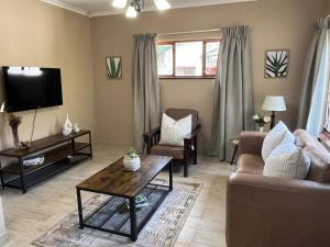 ein Wohnzimmer mit Sofa und Fernseher in der Unterkunft Forest Drive Cottage in Kloof