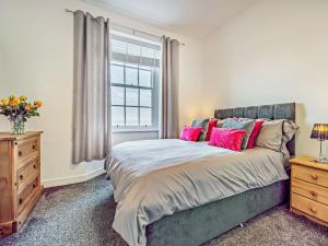a bedroom with a bed with pink pillows and a window at North Lodge Retreat Allonby in Maryport