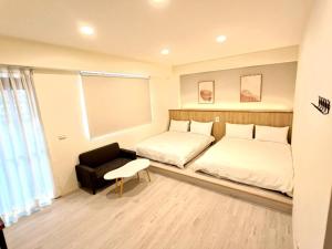 a bedroom with two beds and a chair at 花蓮後站-沐青文旅 in Hualien City