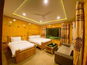 a hotel room with two beds and a couch at Hotel Blangsa Indus View in Skardu