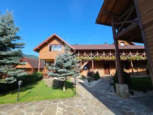a log house with a tree in front of it at Guesthouse Kolo Druziv in Tatariv