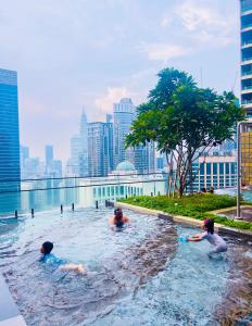 a group of people in a swimming pool with a city skyline at Axon Residence KLCC - KL HOME in Kuala Lumpur