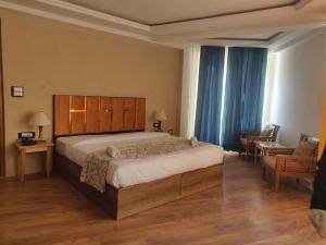 a bedroom with a large bed with a wooden headboard at Kanishka Hotel Ladakh by LexStays in Leh