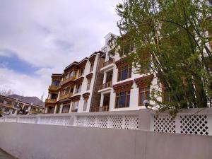 a building with a white fence in front of it at Kanishka Hotel Ladakh by LexStays in Leh