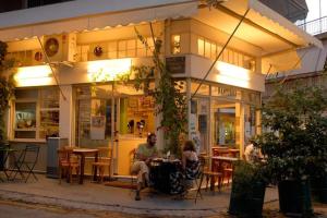 two people sitting outside of a restaurant at night at Bright colourful apartment city center in Athens