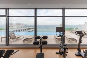 einen Fitnessraum mit Blick auf das Meer und den Pool in der Unterkunft Chill Side - Infinity Pool & Spa Resort in Mamaia Nord – Năvodari