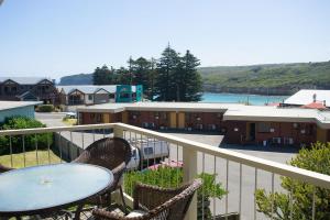 a patio area with tables and chairs and a boat at Loch Ard Motor Inn in Port Campbell