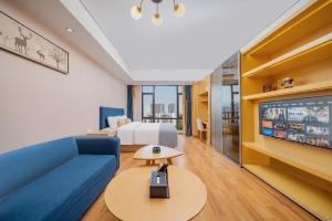una camera d'albergo con un divano blu e un letto di 寓米公寓(琶洲会展中心广州塔店) a Canton