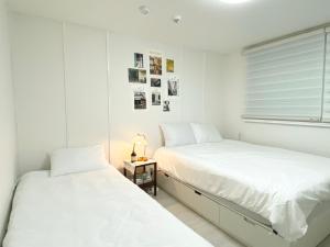 ソウルにあるHongdae Cozy42の白い壁の客室で、ベッド2台、窓が備わります。