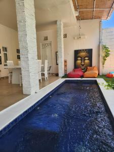 une piscine dans un salon avec un visage sur le mur dans l'établissement Capricorn Villa, à Seminyak