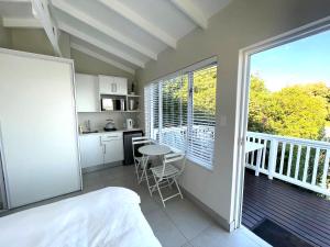 a room with a bed and a kitchen with a balcony at Martin's Cottage in Great Brak River