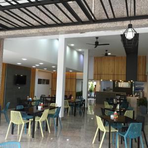 a restaurant with tables and chairs and a kitchen at At Sakon Hotel in Sakon Nakhon