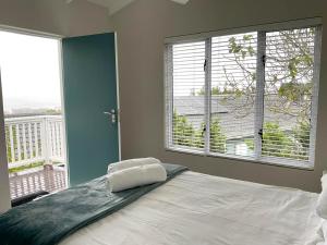 a bedroom with a bed and a large window at Martin's Cottage in Great Brak River