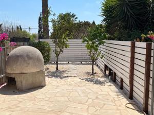 ein Zaun mit einer Steinbank und Bäumen in einem Innenhof in der Unterkunft Regina Gardens - Modern 2 bed maisonette in Paphos City