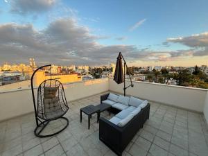 a balcony with a couch and a chair and an umbrella at Palm View Residence with Private Rooftop in Larnaka