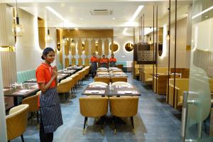 a woman standing in a dining room with tables at Hotel Shreyas Grand Ananthapuramu in Anantapur