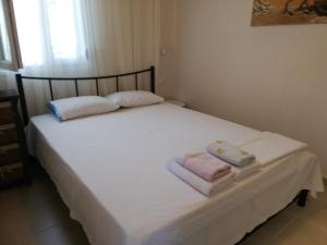 a white bed with two towels on top of it at EFThea Valley in Skála Sikiás