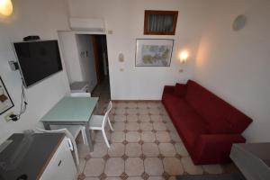 a living room with a red couch and a table at Bilocali ALTAMAREA - zona mare con clima e terrazze in Marina di Campo