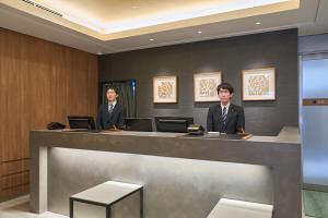 two men in suits sitting at a reception desk at Meitetsu Inn Nagoya Kanayama Annex in Nagoya