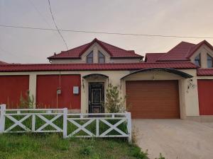 a house with a red garage door and a fence at Luxury Forestside Villa in Quba