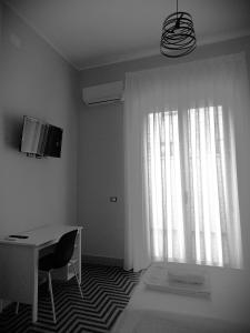 Dieses weiße Zimmer verfügt über einen Schreibtisch und ein Fenster. in der Unterkunft Central Palace in Reggio di Calabria
