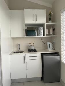 a small kitchen with white cabinets and a microwave at Martin's Cottage in Great Brak River