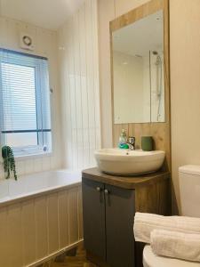 Un baño con lavabo, bañera y espejo. en Rambells Lodge, en Warton