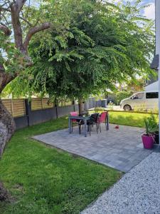 Un patio con una mesa y sillas debajo de un árbol. en Maison a 10 min de la plage, en Ploemeur