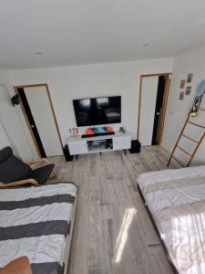 Una sala de estar con dos camas y un televisor de pantalla plana. en Maison a 10 min de la plage, en Ploemeur