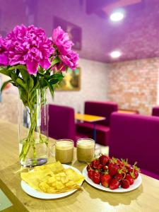 a table with two plates of strawberries and a vase with flowers at Sweet Home in Dnipro +18 photos